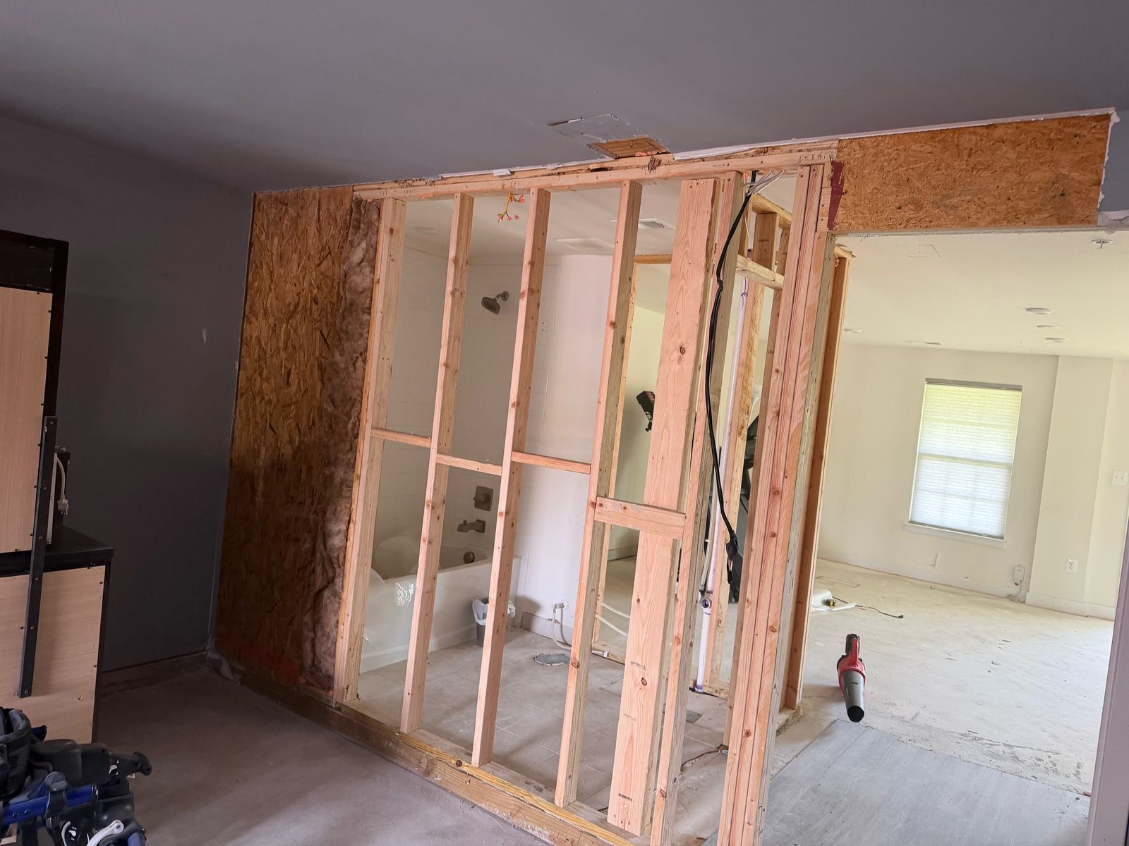 Rebuilt framed wall and OSB sheathing with the bathroom visible through the studs