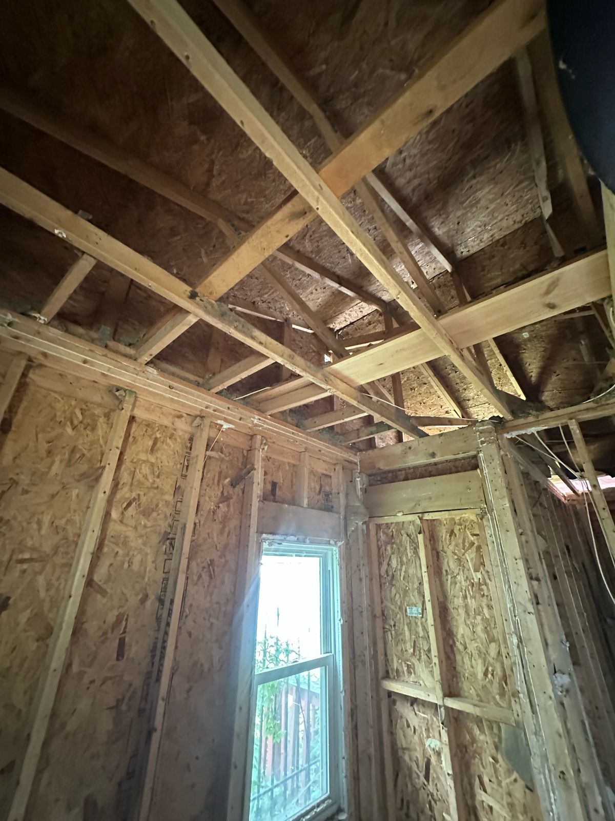 Ceiling joist framing and OSB-sheathed walls around a window
